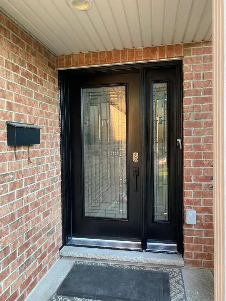 Black double entry door with decorative glass, in red brick with a black mailbox