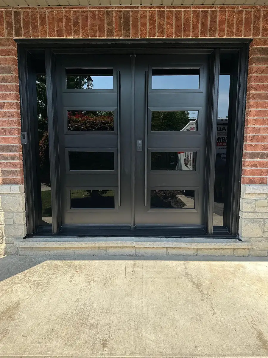 Black double entry door with rows of frosted horizontal glass lites, in a brick entrance