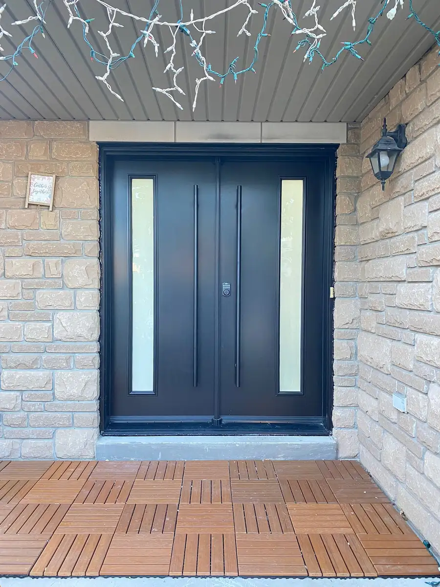 Black double entry door with tall frosted lites, in a stone porch with a teak-tiled step