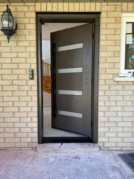 Black entry door with frosted horizontal glass lites, standing open onto the front hall