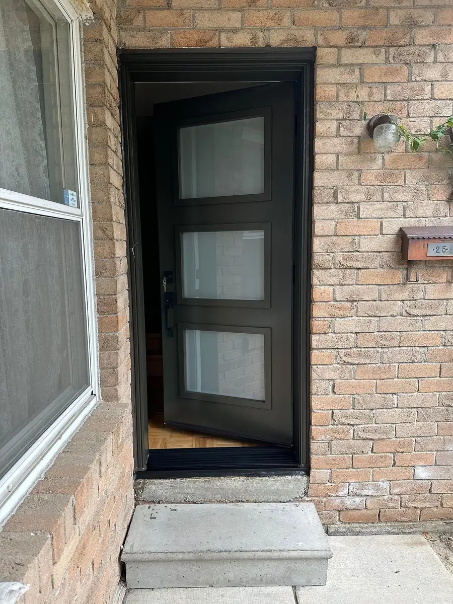 Black entry door with frosted glass lites beside a tall window, at the top of a short concrete step