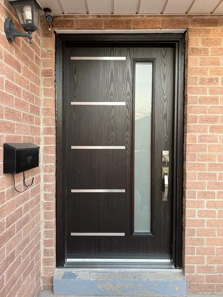 Black woodgrain entry door with horizontal stainless bars and a frosted glass sidelite, in red brick