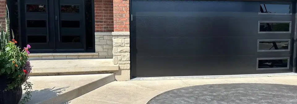 Black flush garage door with side lites next to a matching black double entry door with glass lites