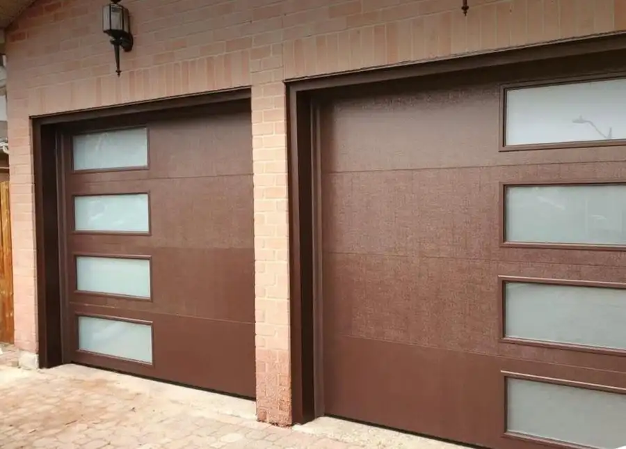 Two brown garage doors with frosted glass lites, side by side in brick