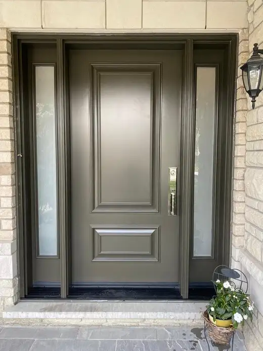 Grey raised-panel entry door with glass sidelites, in a buff brick entrance