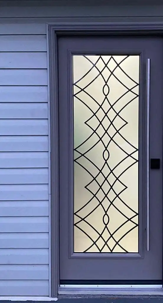 Grey entry door with a full-length decorative leaded glass insert, against lavender siding