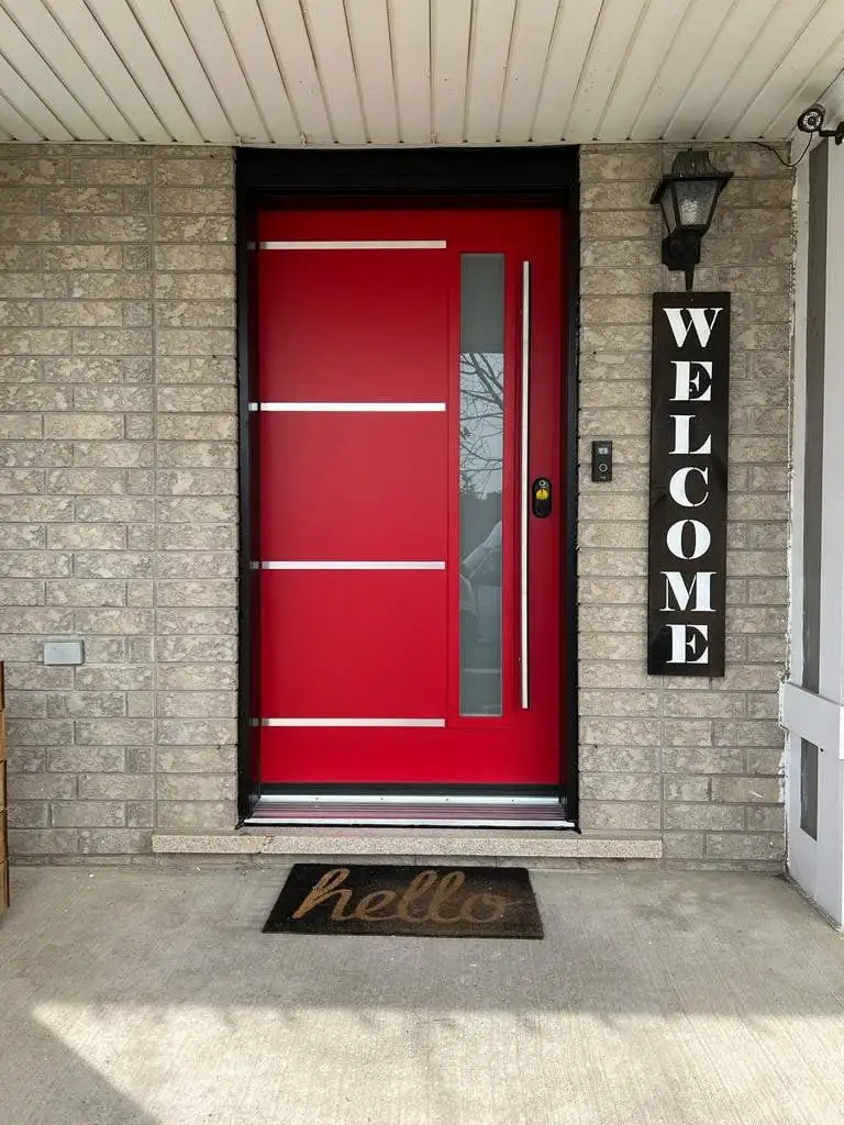 Red modern entry door with a slim frosted glass insert and horizontal stainless bars, under a white soffit